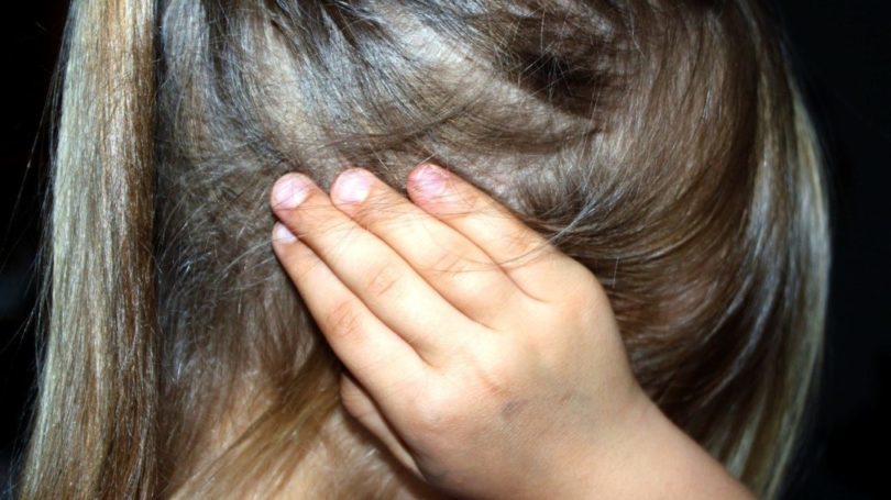 Girl covers her ears in child abuse and custody dispute