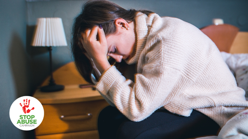 A photo of a sad person holding their head in their bed, indicating an article on depression symptoms, causes, and therapy.