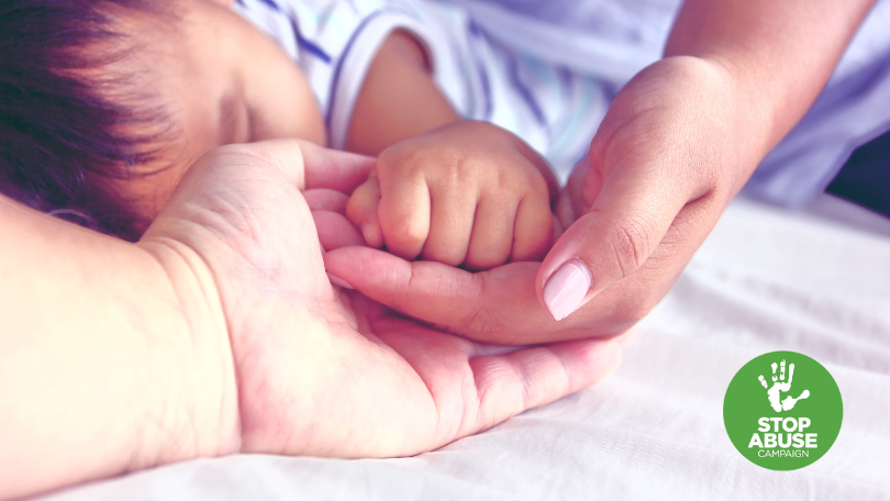 A photo of a woman holding a baby's hand, in an article about Maternal Home Visiting results